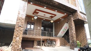A two-story building with a brick facade, a balcony with railings, and a large window. - Shri Laddu Gopal Guest House (Mathura)