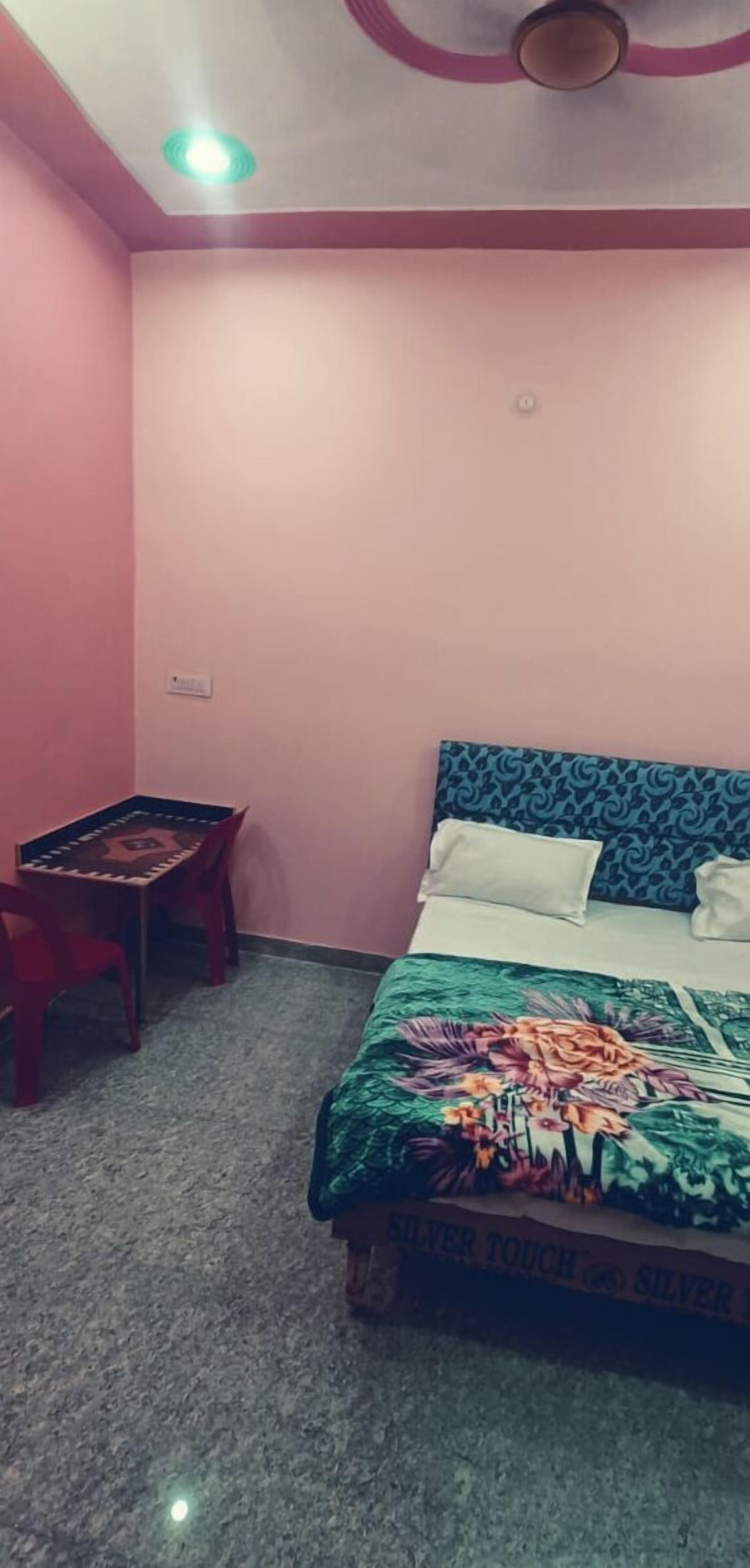 A bedroom with a bed, a table, and a chair.