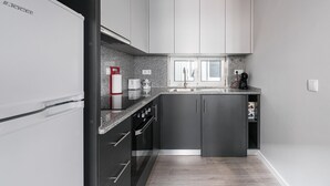 Una cocina compacta con un refrigerador, una cafetera y un tostador sobre la encimera.