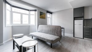 Un espacio habitable moderno y funcional con sofá, mesa de comedor y zona de cocina.