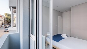 Una habitación de hotel moderna con un ventanal grande, una cama individual y una mesita pequeña.