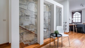Un intérieur moderne avec un mur en pierre, un escalier en bois, un coin repas avec une table et des chaises, et une fenêtre offrant une vue agréable.