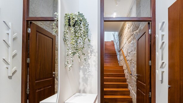 Un couloir moderne avec des portes en bois, une étagère blanche et une plante suspendue.