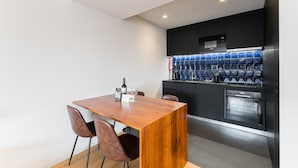 A modern kitchen with a wooden dining table and chairs, a built-in coffee machine, and a stainless steel oven. - GuestReady - Mompilher Apartments (Porto)