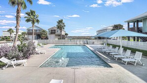 A swimming pool with lounge chairs and palm trees. - Brito Beach- View of Pond | Propane Grill (Port Aransas)
