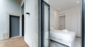 Una habitación de hotel moderna con una cama grande, baño independiente y un pequeño balcón.