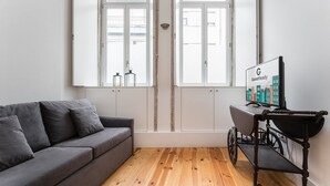 Ein modernes Zimmer mit grauem Sofa, Holzboden und einem Wagen mit einem Schild für GuestReady.