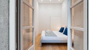 A modern bedroom with a bed, a nightstand, and a window. - GuestReady - Paramount Code Indigo (Porto)