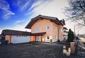 Une maison à deux étages avec un garage, un toit en pente et une allée pavée.
