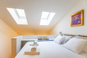 A hotel room with a bed, two skylights, a breakfast tray, and a painting on the wall. - GuestReady - Super cozy 1BDR apartment for 4pax (Porto)