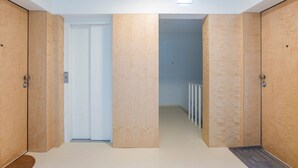 A hallway with wooden doors, a white door at the end, and a radiator in the background.