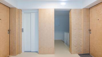Un pasillo con puertas de madera, una puerta blanca al fondo y un radiador en la parte posterior.