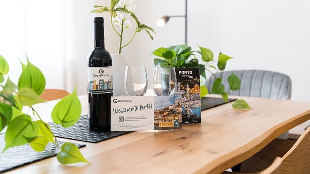Une table en bois avec une bouteille de vin, deux verres et un plan de la ville de Porto.