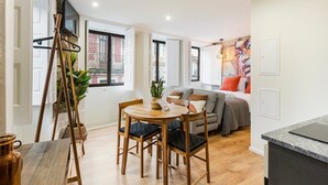 A modern apartment with a dining area, a sofa, and a bed. - GuestReady - Caldeireiros Building (Porto)