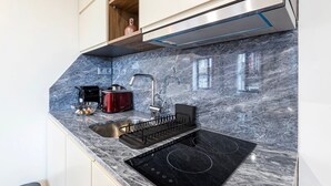 A kitchen with a black stovetop, a sink, and a wooden cabinet above the sink. - GuestReady - Caldeireiros Building (Porto)