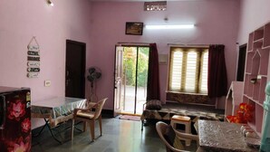 Una habitación con paredes rosas, una mesa de comedor con sillas, un ventilador y una ventana con cortinas.