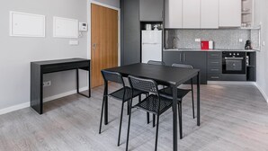 A modern kitchen with grey cabinets, a black dining table, and a built-in oven. - GuestReady - Olivieri's House - 6 (Porto)