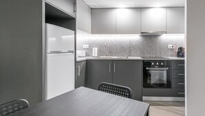 Una cocina moderna con horno empotrado, refrigerador y comedor con mesa y sillas.