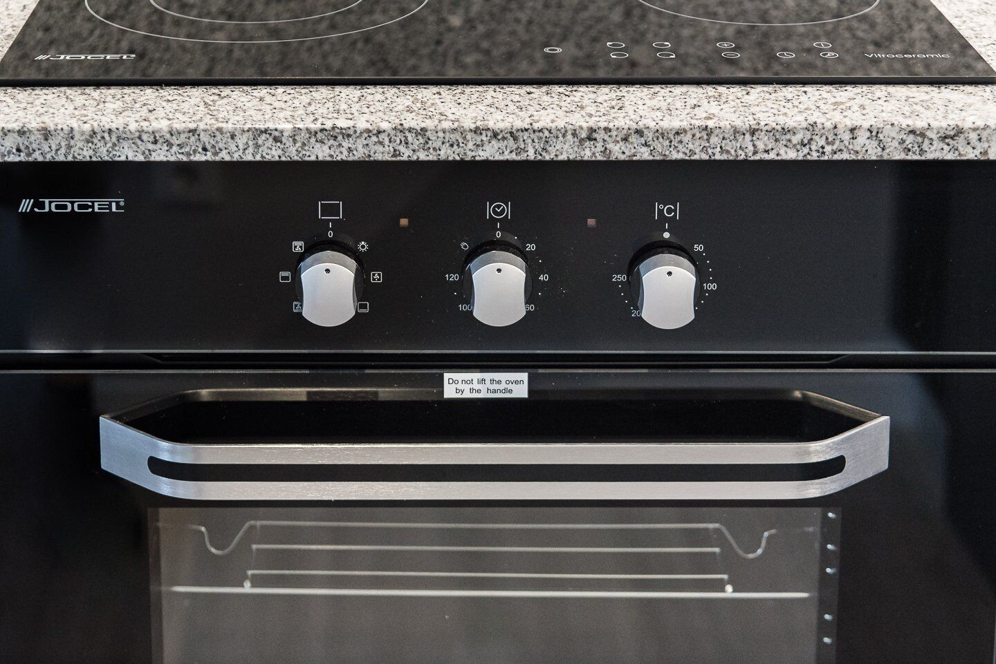 A JOCEK oven with three temperature control knobs and a warning label.