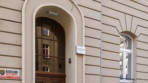 A building with a large wooden door and a green scooter parked outside. - Comfortable Studio in the Center of Katowice | For 3 People (Katowice)