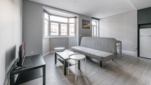 A modern living room with a sofa, a dining table, and a TV. - GuestReady - Olivieri's House - 7 (Porto)