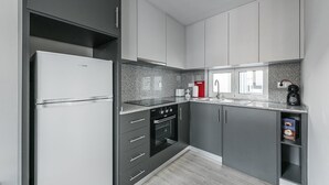 A modern kitchen with grey cabinets, a white refrigerator, a built-in oven, and a coffee maker. - GuestReady - Olivieri's House - 7 (Porto)