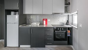 Une cuisine compacte avec des meubles de couleur sombre, un four encastré et un plan de travail en granit.
