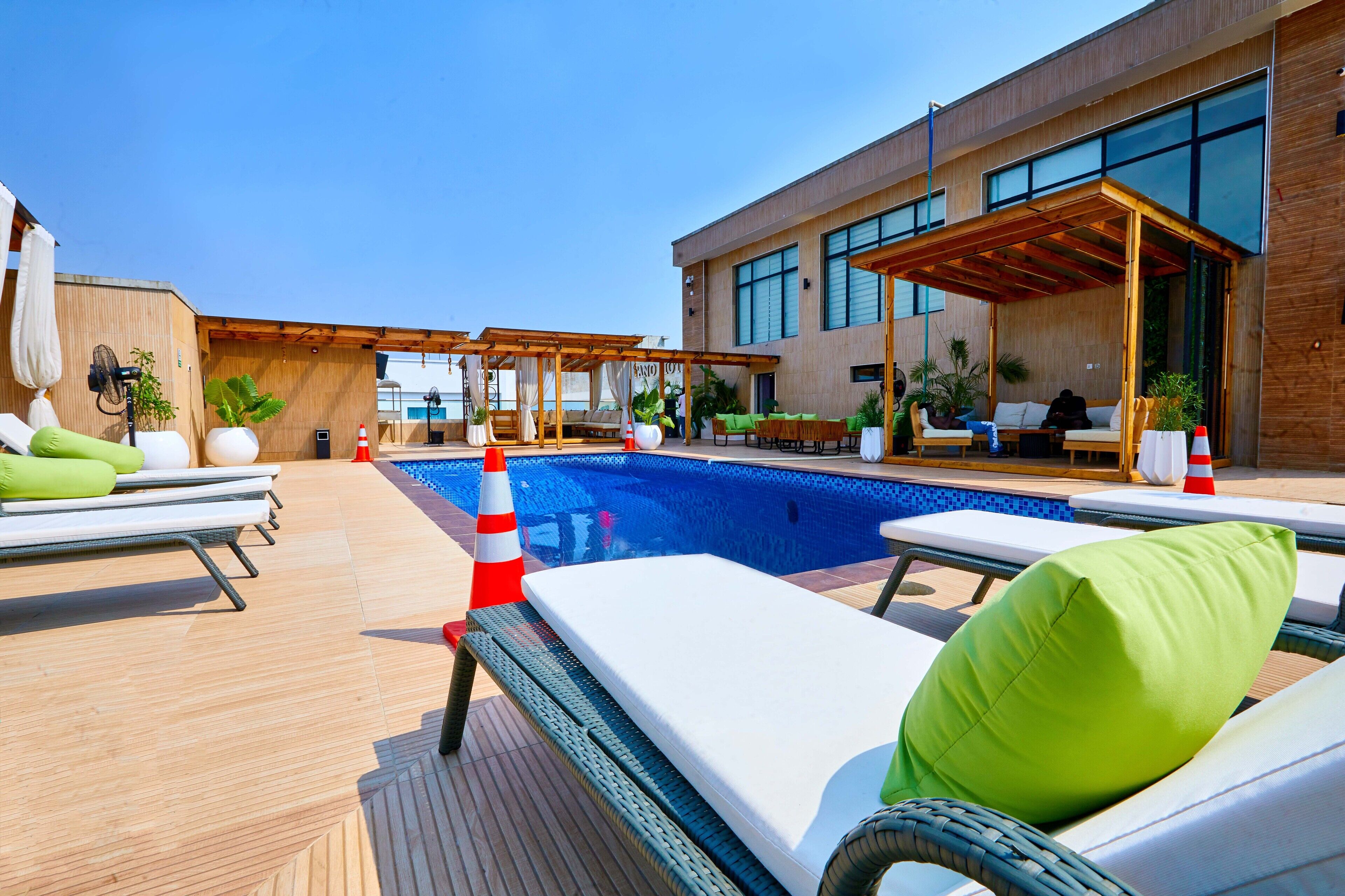 A rooftop pool area with lounge chairs, a swimming pool, and a modern building with large windows.