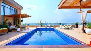 A rooftop swimming pool with lounge chairs and a city view. - Vintano Hotel (Lekki)