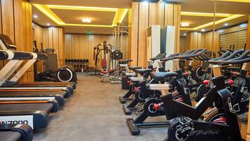 Un gimnasio con cintas de correr, bicicletas estáticas y máquinas de pesas.