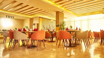 Un comedor moderno con una mesa larga y varias sillas, techo de madera con diseño de cuadrícula, y un espacio luminoso y bien iluminado con ventanas amplias.