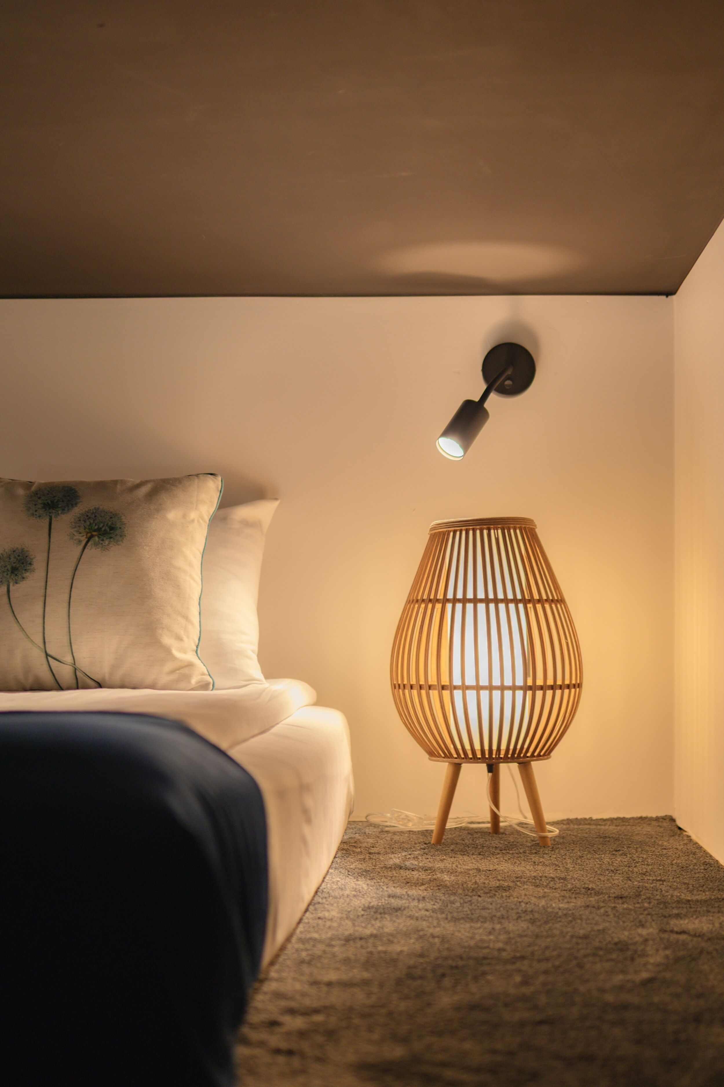 A bedroom with a bed, a wall-mounted lamp, and a floor lamp.