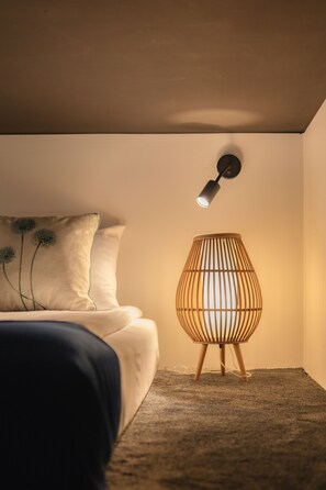 A bedroom with a bed, a wall-mounted lamp, and a floor lamp.