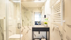 A modern bathroom with a glass-enclosed shower, a black vanity with a sink, and a marble backsplash. - Motto Gdańsk (Gdansk)
