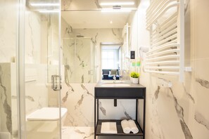 A modern bathroom with a glass-enclosed shower, a black vanity with a sink, and a marble backsplash. - Motto Gdańsk (Gdansk)
