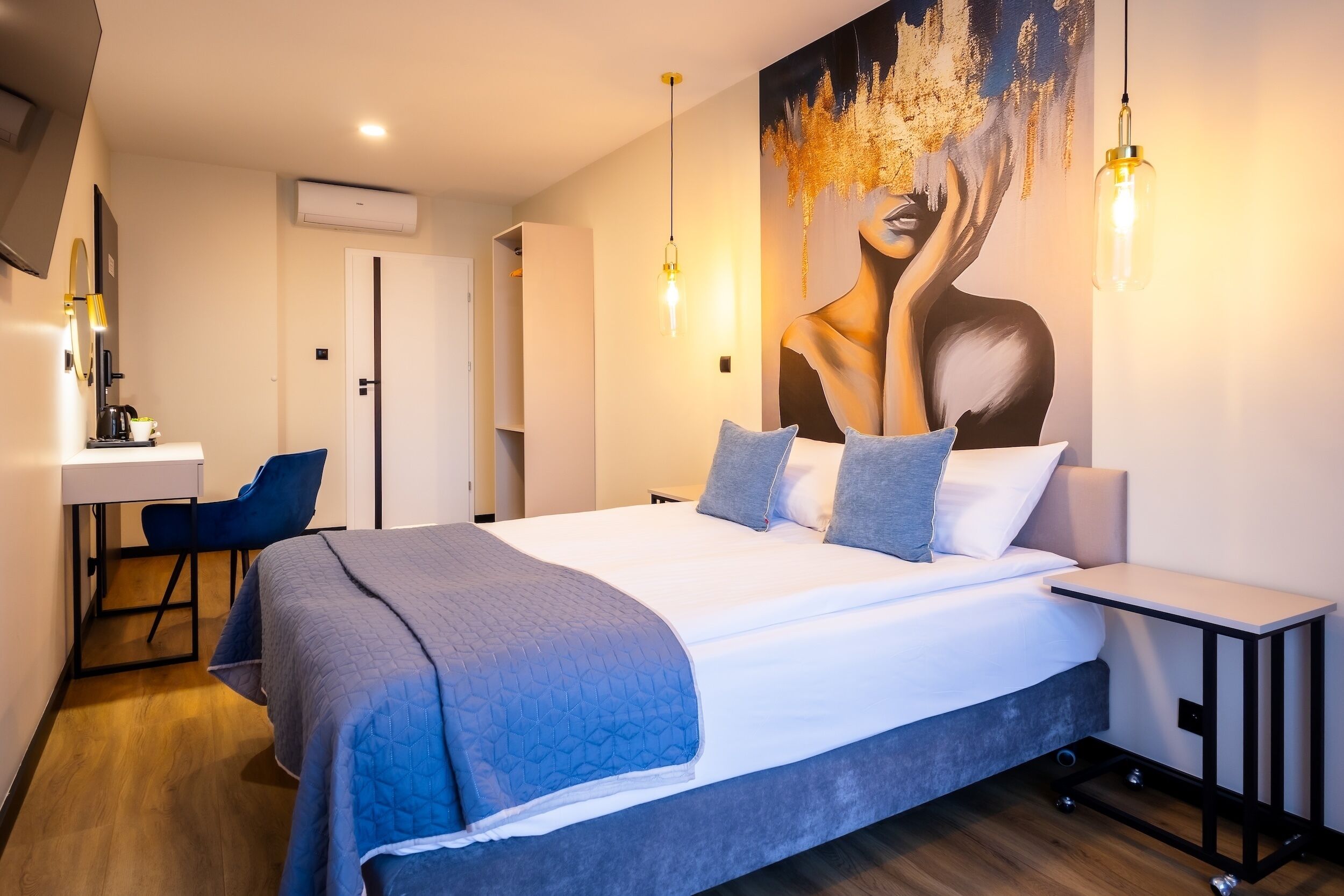 A modern hotel room with a large bed, a desk, and a chair.