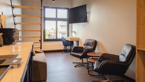 A modern office space with a desk, two leather chairs, a large window, and a mounted TV. - Motto Gdańsk (Gdansk)