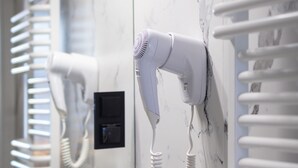 A bathroom with a hairdryer mounted on the wall, a towel rack, and a small potted plant. - Motto Gdańsk (Gdansk)
