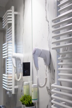 A bathroom with a hairdryer mounted on the wall, a towel rack, and a small potted plant. - Motto Gdańsk (Gdansk)