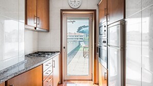 A modern kitchen with wooden cabinets, a stainless steel refrigerator, and a built-in oven. - GuestReady - Portrait with a view (Porto)