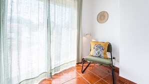 A room with a chair, a woven wall hanging, and a curtain. - GuestReady - Portrait with a view (Porto)