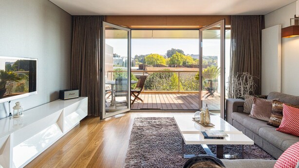 Ein modernes Wohnzimmer mit einer Couch, einem Couchtisch und einem Balkon mit Tisch und Stühlen.