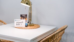 A white table with a gold desk lamp, a "Welcome to Porto" sign, and a city map of Porto. - GuestReady - Road to Revolution (Porto)