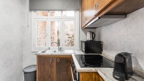 A compact kitchen with a sink, stove, and microwave. - GuestReady - Road to Revolution (Porto)