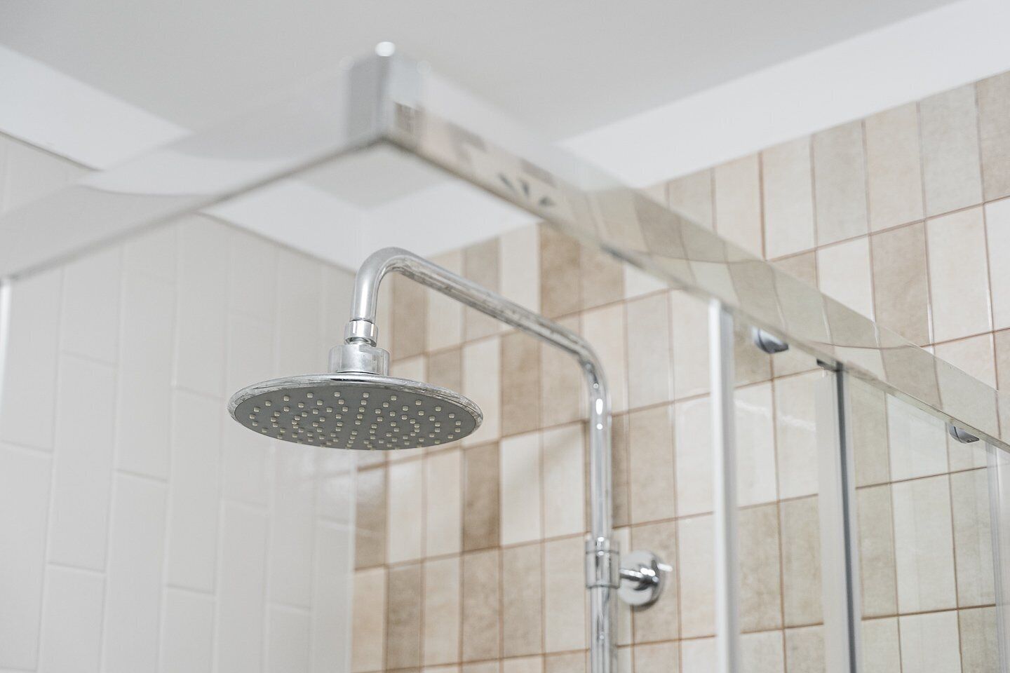 Een douche met een handdouche en een bedieningskraan aan de muur.