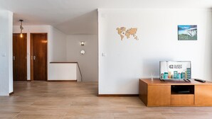 A hotel lobby with a wooden floor, a reception desk, a world map decoration, and a painting on the wall.
