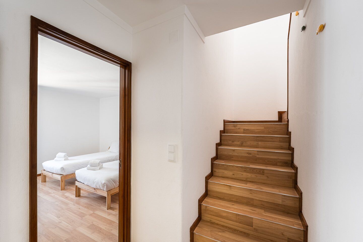 Un escalier en bois mène à une chambre dotée de deux lits.