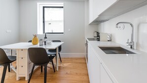Une cuisine moderne avec des meubles blancs, une table à manger en bois et un évier encastré.