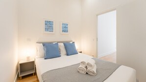 Une chambre à coucher avec un lit, deux oreillers, une table de chevet, une lampe et une fenêtre.