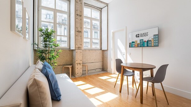 Un salon moderne avec un canapé, une table à manger et des chaises, de grandes fenêtres et une affiche accrochée au mur.